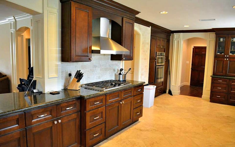 Spacious kitchen with dark wood cabinetry, granite countertops, gas cooktop, stainless steel range hood, and light wood flooring