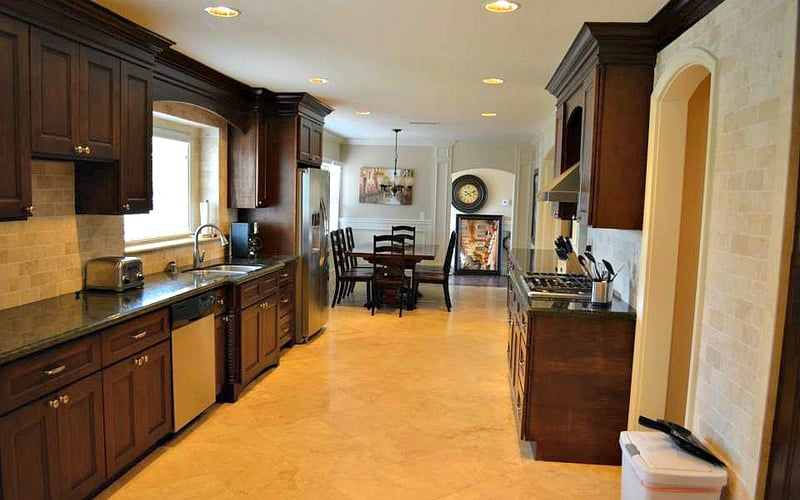 Large open-plan kitchen with dark wood cabinets, stainless steel appliances, and dining area visible in background.